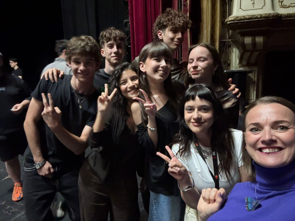 WhatsApp Image 2026-06-22 at 121319 - Teatrul Regina Maria Oradea Group of young people posing closely for a selfie backstage, smiling at the camera.